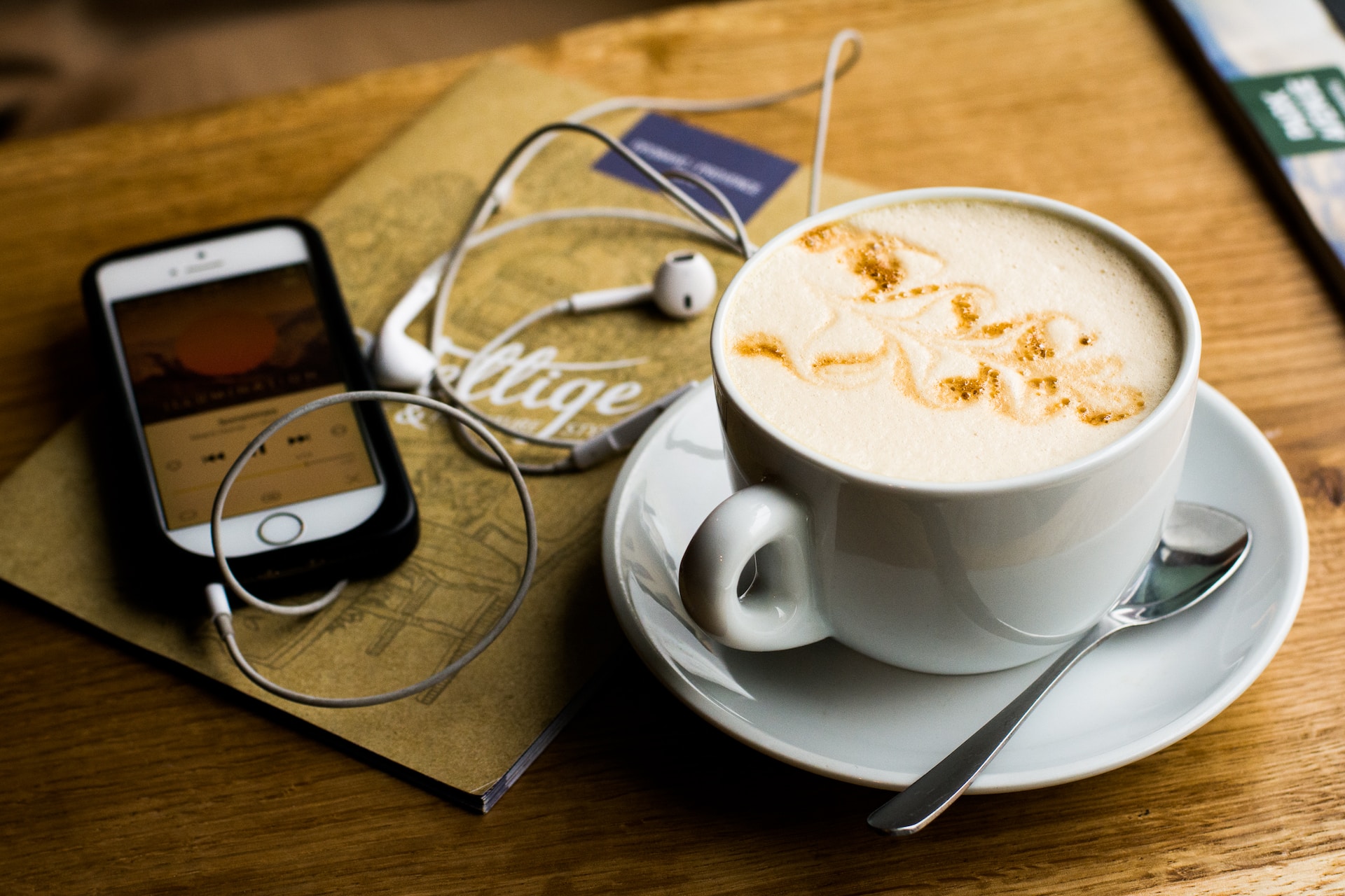 uma mesa com caderno, café e um celular preparado para reproduzir a audiosérie Paciente 63 do Spotify 