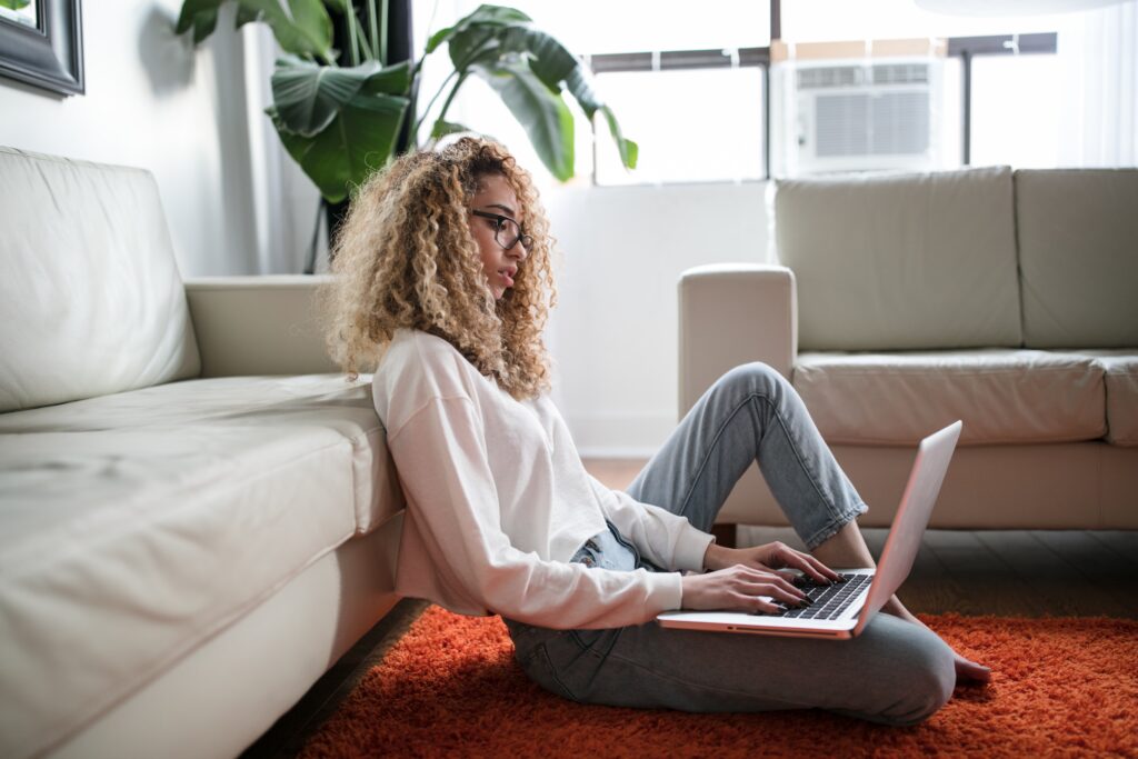 Menina sentada no chão se preparando para comprar no Mega Oferta Amazon Prime 2023 utilizando o notebook apoiado no colo