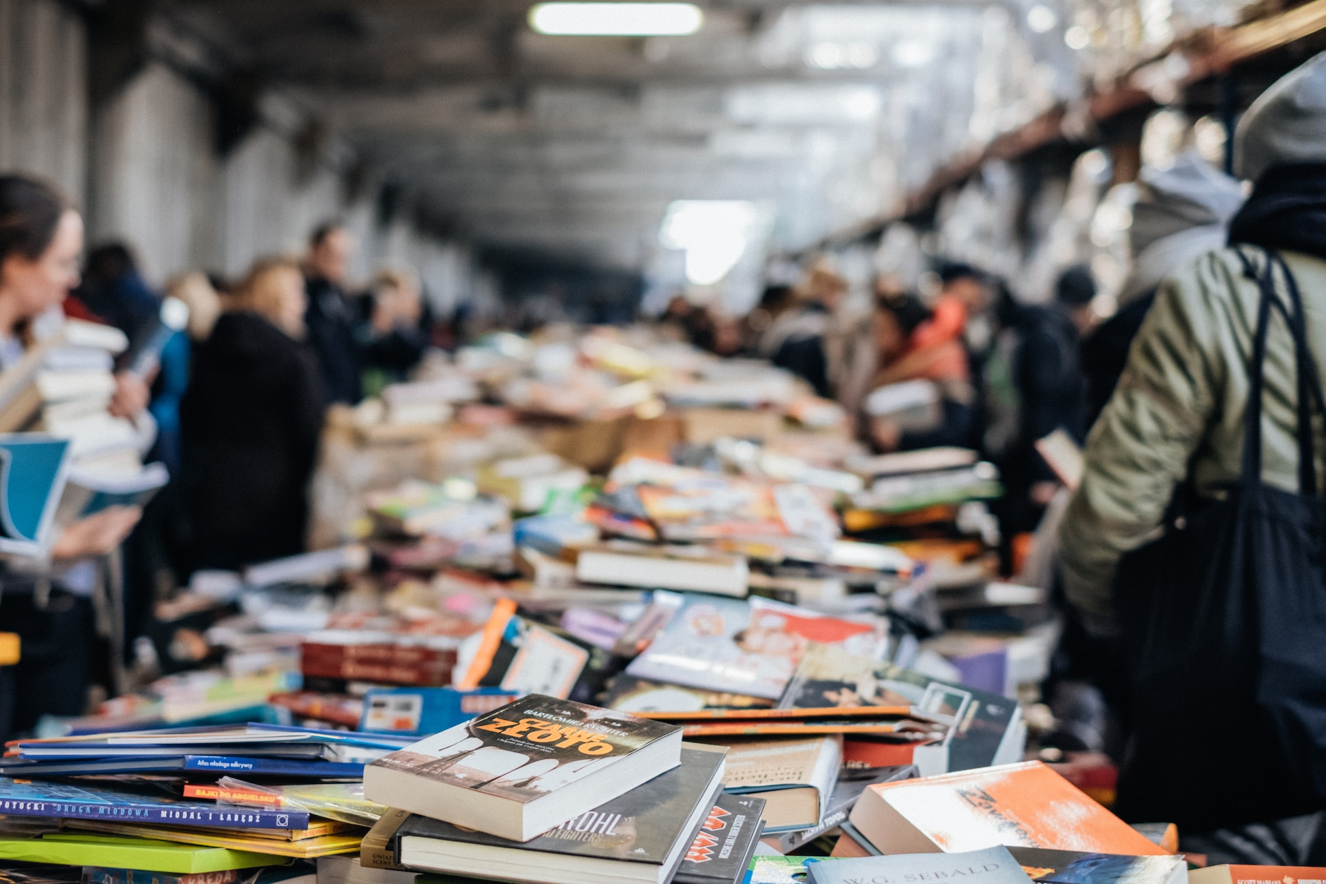 bienal do livros com pessoas passando e olhando pilhas de livros